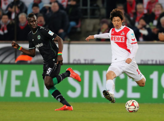 COLOGNE, GERMANY - FEBRUARY 21: Yuya Osako of Cologne (R) kicks the ball beside Salif Sane of Hannover during the Bundesliga match between 1. FC Koeln and Hannover 96 at RheinEnergieStadion on February 21, 2015 in Cologne, Germany. 